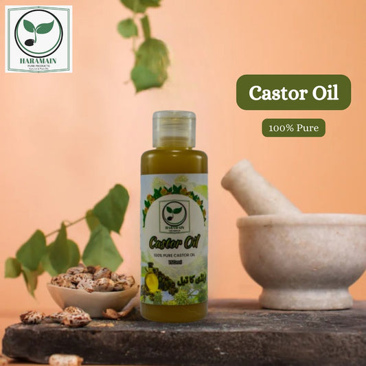 Bottle of castor oil with a mortar and pestle on a stone surface, against a peach-colored background.