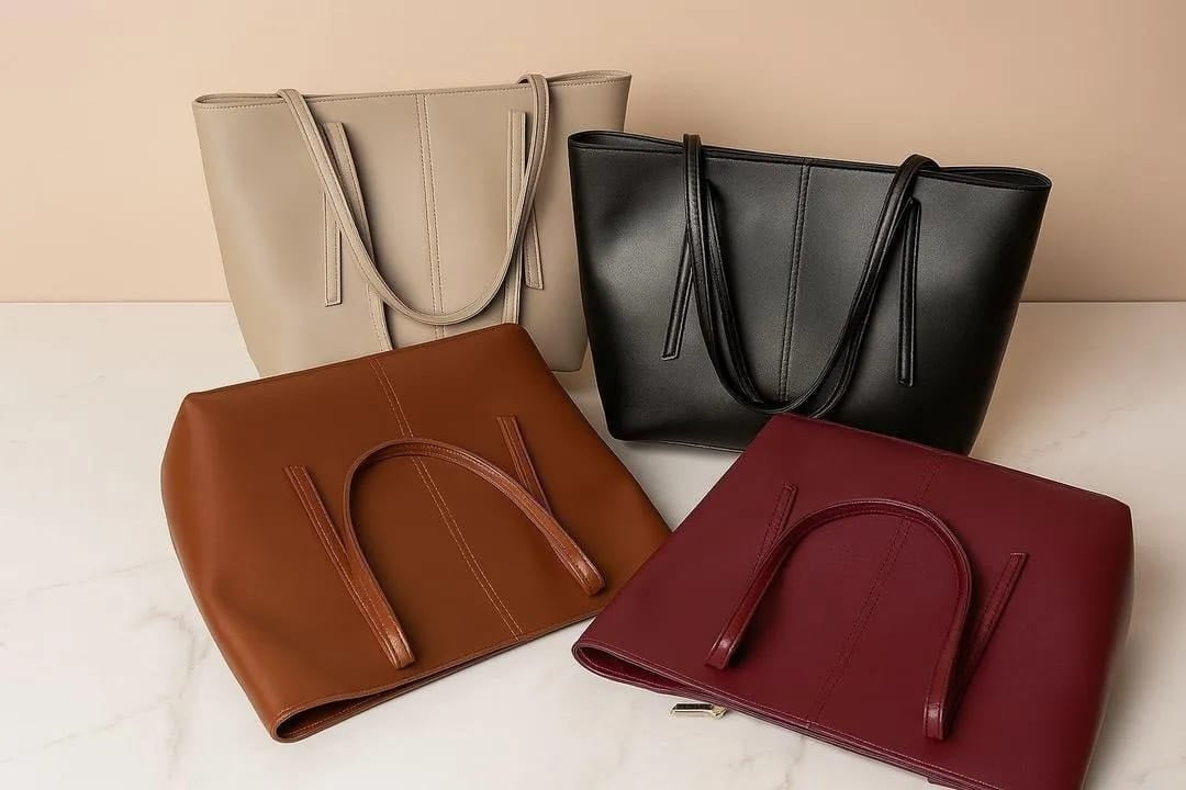 Four handbags in beige, black, brown, and red on a light surface with a beige background