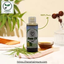 Bottle of Neem oil with a glass container and leaves on a wooden surface, featuring the brand 'Haramain Neem'.