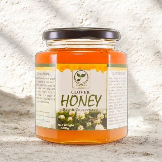 Jar of clover honey with a label on a textured surface
