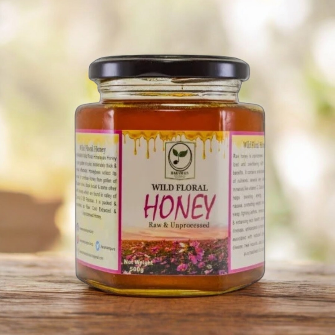Jar of wild floral honey on a wooden surface with a blurred natural background
