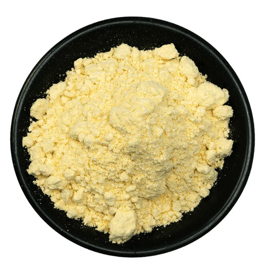 Yellow powder in a black bowl on a white background