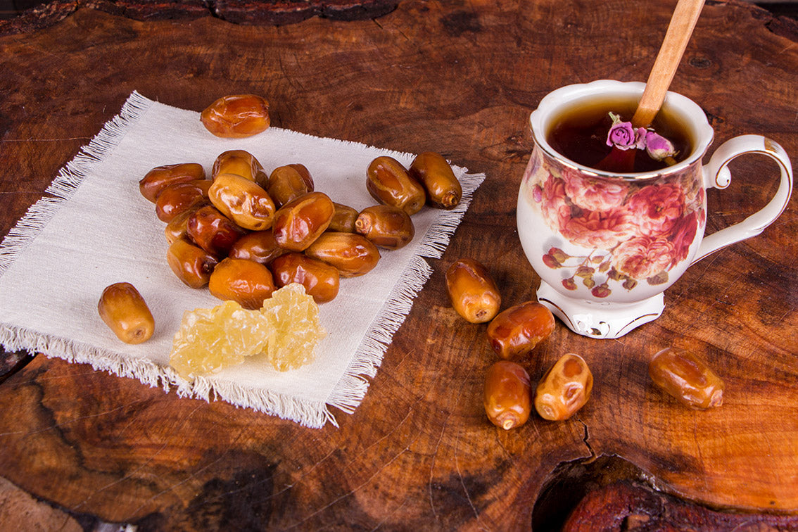 Tea cup with a spoon, dates, and honey on a wooden surface