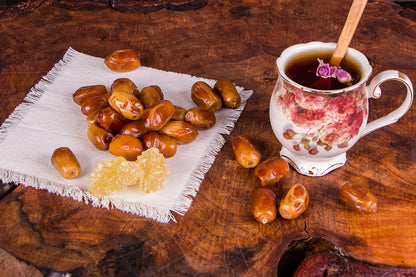 Tea cup with a spoon, dates, and honey on a wooden surface